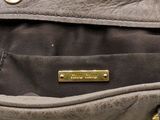 the inside of a gray purse with a gold plated handle