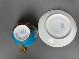 a blue and white plate with a gold handle next to a blue and white plate with a gold handle