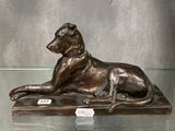 statue en bronze représentant un chien couché sur une table, exposée dans une vitrine