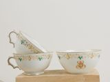 two cups and saucers sitting on a wooden block on a table