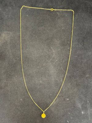 a gold necklace with a yellow pendant on a black background