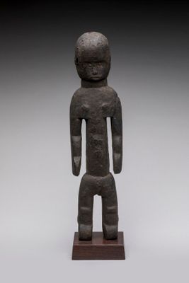 une statue représentant un homme debout sur un socle en bois