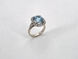 a close up of a ring with a blue topaz stone and diamonds