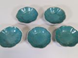 four small blue bowls sitting on top of a white table