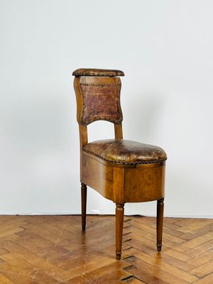 chaise en bois avec assise en cuir, posée sur un parquet