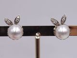 pair of pearl and diamond earrings on a black stand