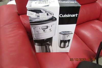 une cafetière encore dans son emballage, posée sur un canapé en cuir rouge