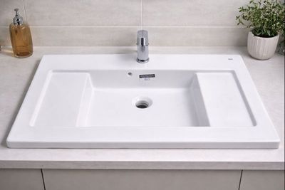 un lavabo blanc posé sur un plan de travail dans une salle de bains