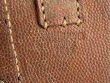 close up view of a brown leather bag with a metal button