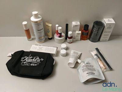 un sac noir posé sur une table, rempli de produits de beauté