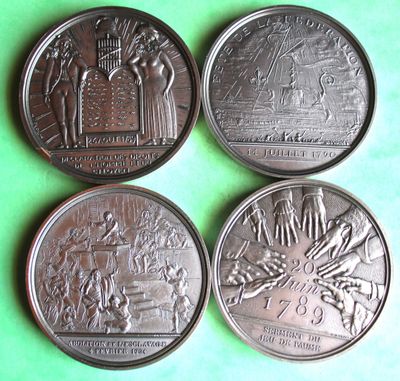 four commemorative coins of different sizes and shapes on a green surface