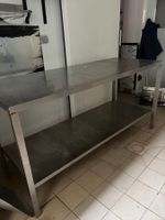 Une table inox avec tablette entre jambe.