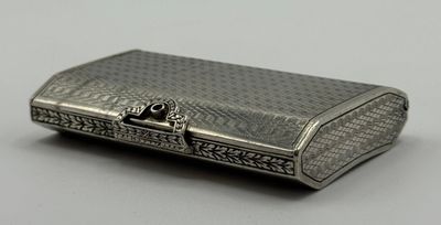 un étui à cigarettes ancien en argent posé sur une table, sur fond blanc