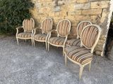 four chairs are lined up against a stone wall in front of a brick wall