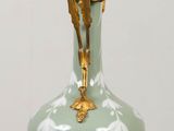 a green vase that has a gold decoration on it