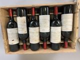 six bottles of red wine in a wooden crate on a table