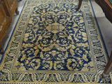 un tapis bleu et or posé sur le sol, à côté d'une commode