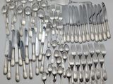a lot of silver spoons and forks laid out on a table
