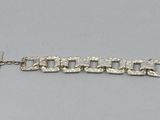 silver plated bracelet with links and clasps on a gray surface