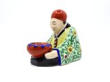 a figurine of a man with a bowl on his lap