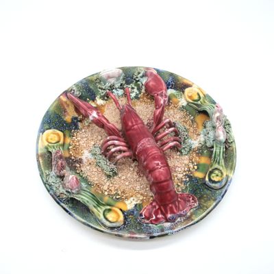 une assiette sur laquelle est posé un homard rouge, posée sur une table blanche