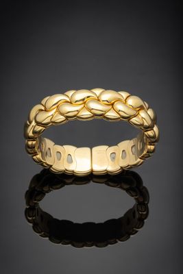 une bague tressée en or jaune sur un fond noir