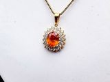 an image of a necklace with an orange stone surrounded by diamonds