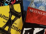 trois livres sont posés sur une table recouverte d'une nappe blanche