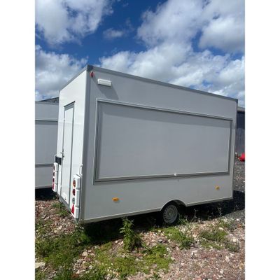 a white trailer parked in a field with a sky in the background