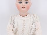 an old doll with a white dress sitting on a white surface