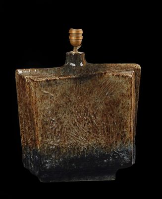 un vase marron et noir posé sur une table noire