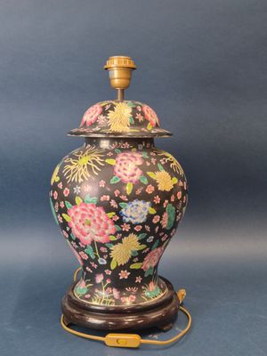 un vase noir et doré orné de fleurs sur fond bleu