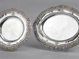 une paire de plats plaqués argent posés sur des socles, disposés sur un support gris