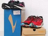 une paire de chaussures de course rouges et noires posée sur une boîte en carton