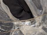 a person holding a piece of luggage that is wrapped in plastic
