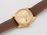 an image of a gold watch with brown leather strap on a white surface