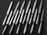 six knives are lined up in a row on a black surface
