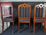 three wooden chairs are lined up against a black backdrop