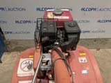 an image of a red lawn mower parked in front of a wall