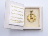 a small gold medal in a white box on a table