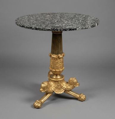 une table plaquée or avec un plateau en marbre reposant sur un piédestal