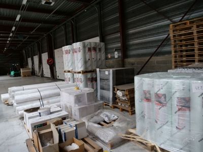 de nombreux rouleaux de film alimentaire empilés sur des palettes dans un entrepôt
