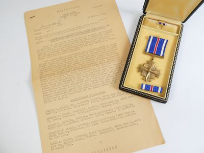 deux médailles dans une boîte posée sur une table, à côté d'une lettre