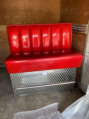 un banc rouge dans une pièce où un journal est posé par terre