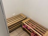 un parquet en bois massif dans une salle de bains aux murs blancs, avec une étagère en bois pour les chaussures