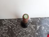 a bottle of wine sitting on a table next to a pair of red shoes