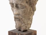 une image représentant une sculpture représentant une tête posée sur un bloc de bois
