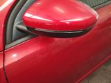 a close up of a red car with a side view mirror