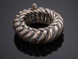 a silver ring with a twisted design on a black surface