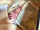 beaucoup d'argent dans un sac d'où sort un bout de papier